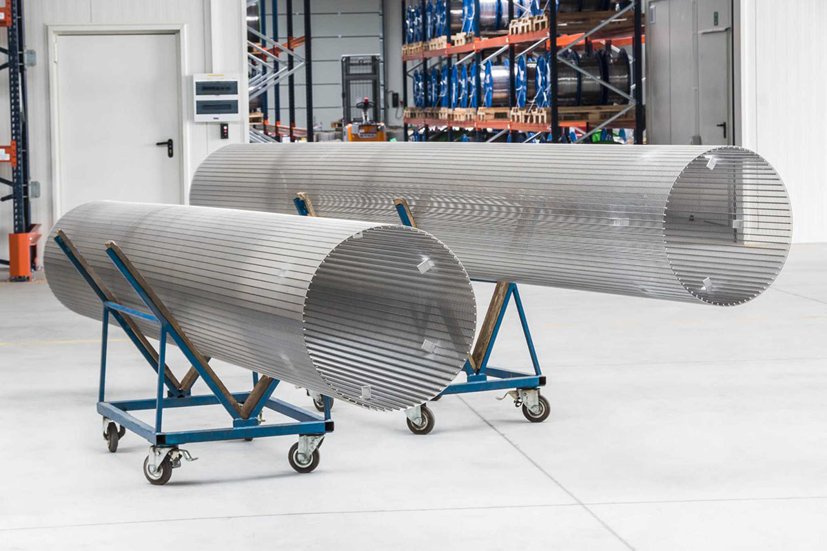 Two stainless steel wedge wire cylinders on wheeled supports in a manufacturing partner workshop